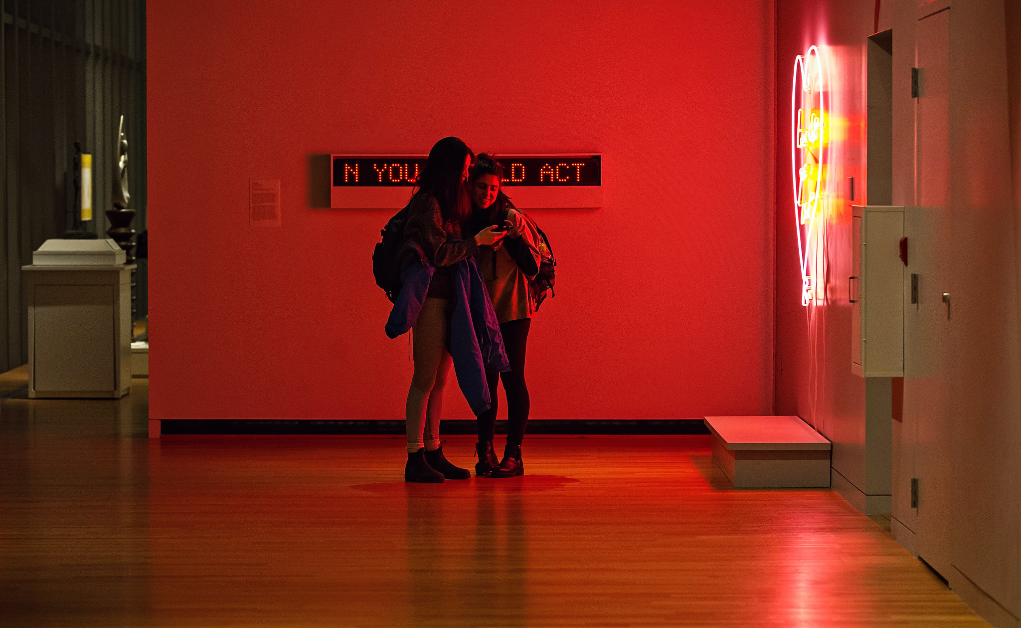Two girls standing in front of a neon light