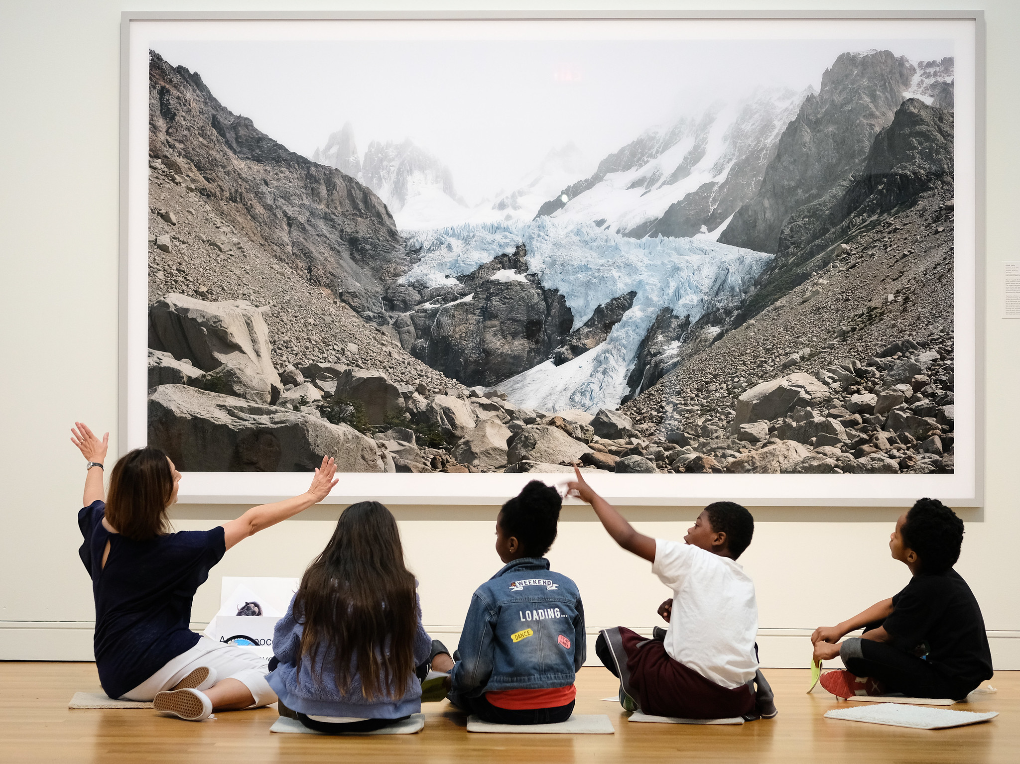 A group of children sitting in front of a photograph of a mountain