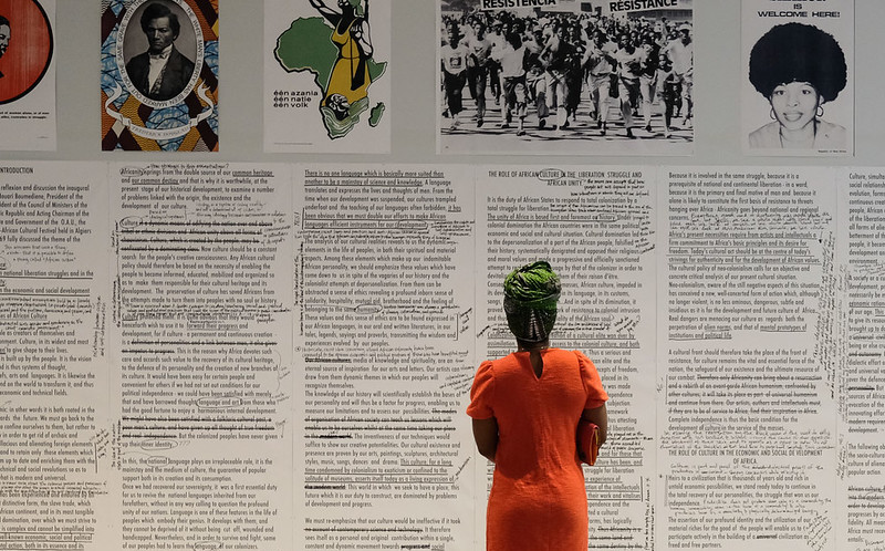 A student in the foreground reads a wall sized work from the Pan-African Pulp exhibition.