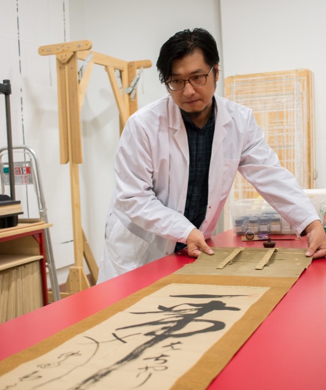 Qian He inspects a scroll in UMMA's Robert B. Jacobs Asian Art Conservation Laboratory