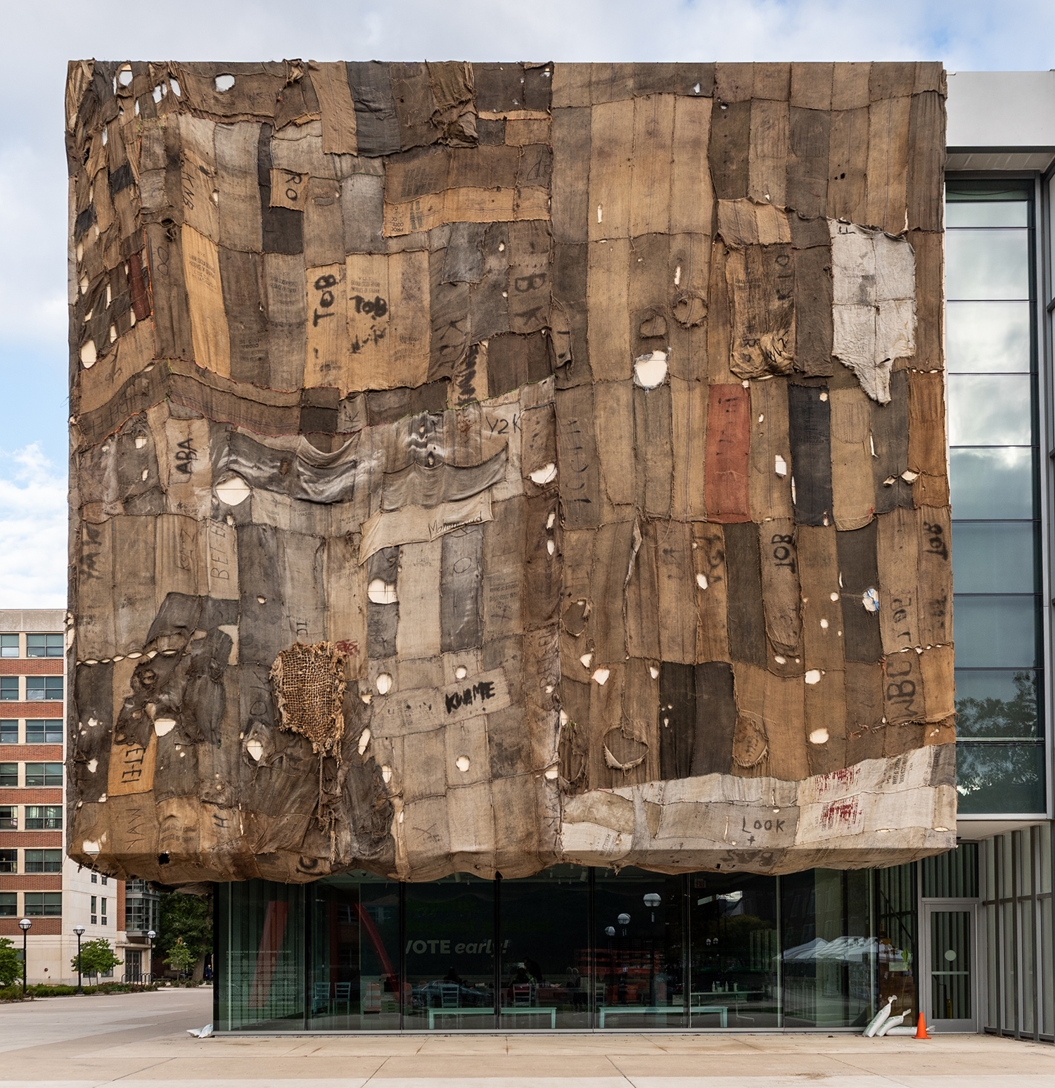 The front of UMMA's building, covered with a patchwork quilt made of various brown burlap sacks