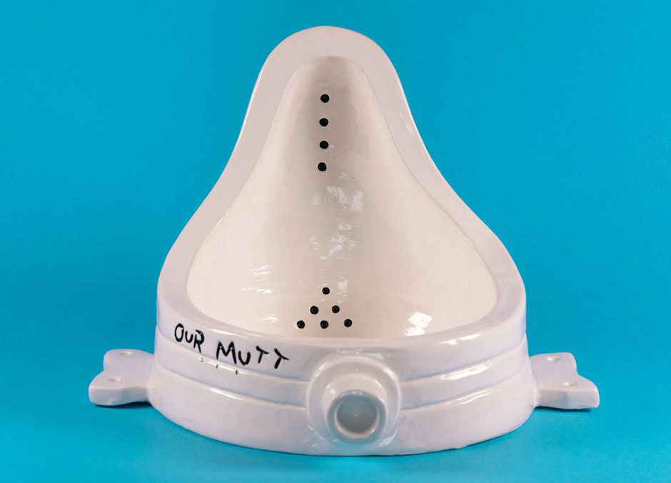 A white ceramic shaped like a urinal placed on its back. the words "Our Mutt" are hand painted around the rim