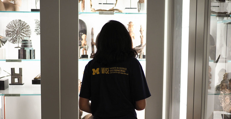 A student looks into one of UMMA's open storage cabinets containing a variety of objects from UMMA's collection.